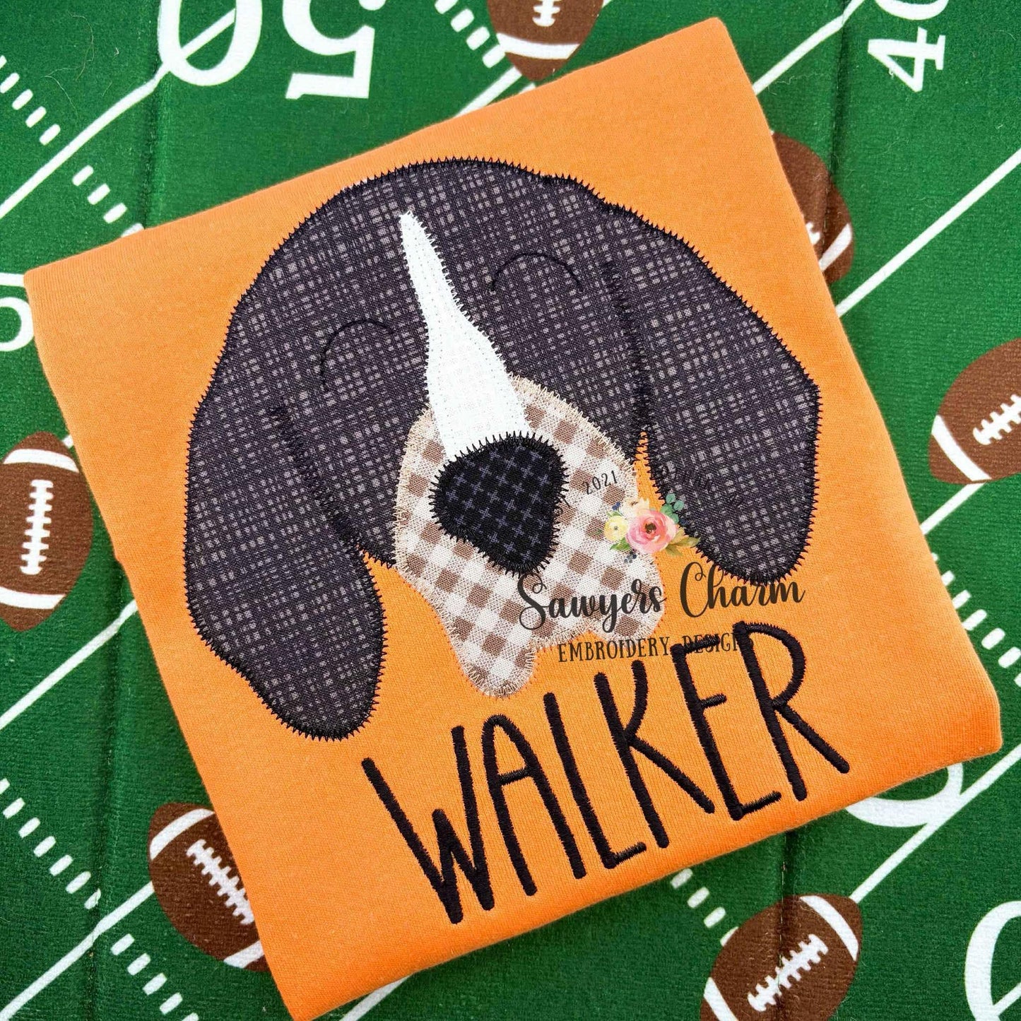 Embroidered patch of a dog with 'Walker' on an orange background, on a sports-themed fabric.