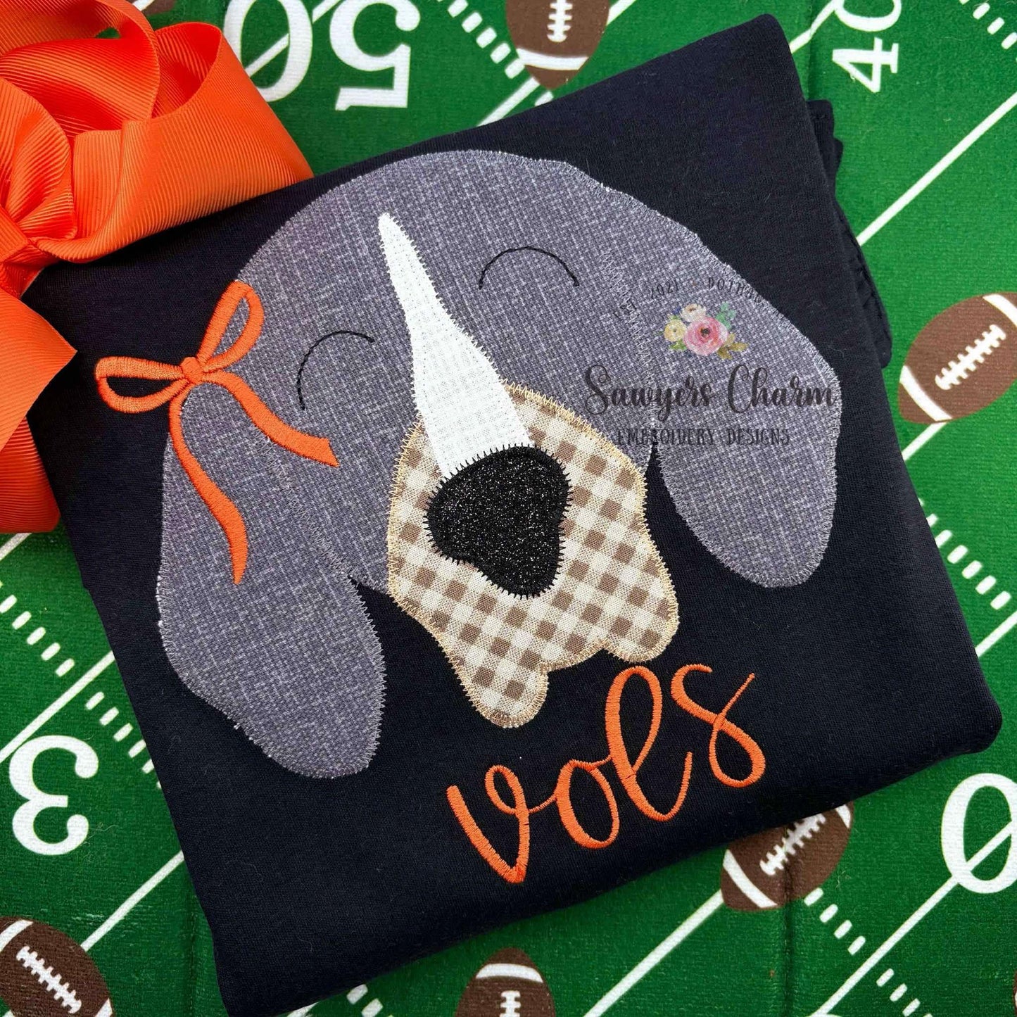 Embroidered dog patch with 'vols' on a black background, surrounded by football-themed decor.