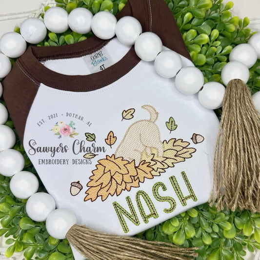 Children's t-shirt with 'Sawyer's Charm' design on a decorative wreath with tassels and beads.
